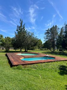 a pool with a wooden deck in the grass at Greenfern Lodge and Chalets in Kafferkop