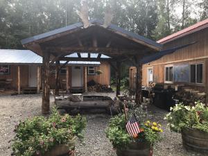 a wooden cabin with an american flag in a yard at talkeetna villas and tours in Talkeetna