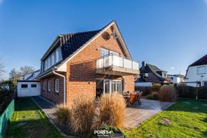 a brick house with a balcony on a patio at Ferienhaus Buhne 23 in Büsum