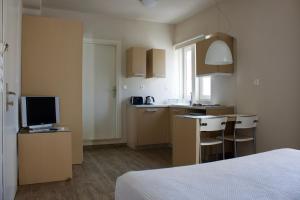 a room with a bed and a kitchen with a television at Notos Luxury Studios in Katelios