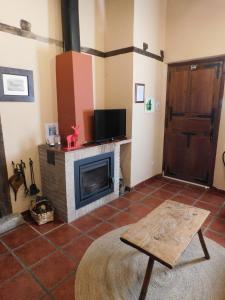 Una sala de estar con chimenea y televisión. en Casas Rurales Cimera yBrincalobitos, en Hoyos del Espino