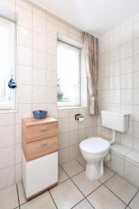a white bathroom with a toilet and a window at Haus Kajedeich FeWo Robbe in Bensersiel