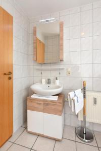 a white bathroom with a sink and a mirror at Haus Kajedeich FeWo Robbe in Bensersiel