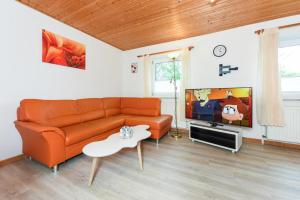 a living room with an orange couch and a tv at Haus Hafeneck FeWo Flut in Bensersiel