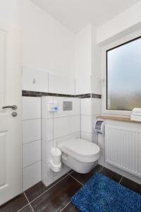 a white bathroom with a toilet and a window at Haus zur Möwe FeWo Möwe 2 in Bensersiel