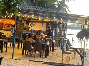 a group of people sitting at a restaurant on the beach at Moonhut Bungalows in Mae Nam