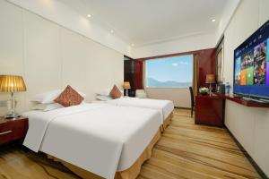 a hotel room with two beds and a flat screen tv at Yanling Hotel in Guangzhou