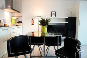 a dining room table with black chairs and a vase with flowers at Holidays 15K Empuriabrava in Empuriabrava
