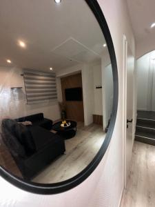 ein Spiegel, der ein Wohnzimmer mit einer Couch widerspiegelt in der Unterkunft logement indépendant proche Colmar parking wifi in Wintzenheim