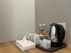 a coffee maker on a tray with cups and water bottles at Serapi Verdure Hotel in Kuching