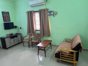 a room with a bed and chairs and a tv at Golden Service Apartment in Tiruchirappalli