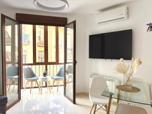 グラナダにあるAlhambra Centro Apartamentoのテーブルと椅子とテレビのあるリビングルーム
