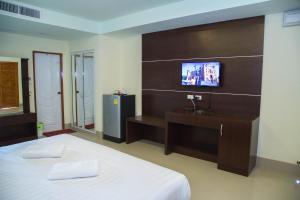 a bedroom with a bed and a tv on a wall at Smile Residence in Rawai Beach