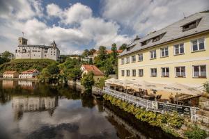 a river in a town with buildings and a castle at Rožmberk Inn in Rožmberk nad Vltavou