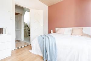 a bedroom with a white bed with pink walls at Villa Plage Ensorpark in Ostend