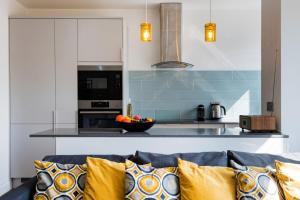 a living room with a couch and a kitchen at Bright and Modern Earls Court Gem in London