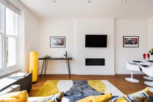 a living room with a couch and a tv on a wall at Bright and Modern Earls Court Gem in London