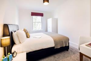 a bedroom with a bed with white walls and a window at Bright and Modern Earls Court Gem in London