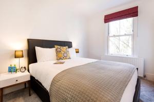 a bedroom with a large bed and a window at Bright and Modern Earls Court Gem in London +9 photos
