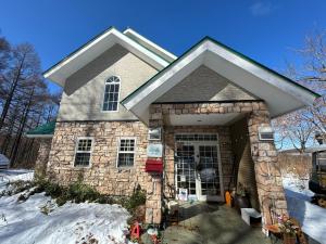 a stone house with a front door in the snow at Echoland Madarao エコーランド斑尾 All en-suite rooms & a free 3-minute shuttle to the ski resort in Madarao Kogen