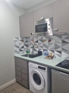 a kitchen with a washing machine and a microwave at Hotel Apartamento Bajamar in Las Palmas de Gran Canaria