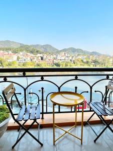 a table and chairs on a balcony with a view of the water at Chi's House Cao Bang in Hoàng Ngà