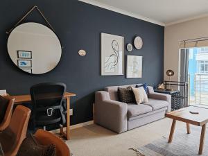 a living room with a couch and a mirror at Cove Retreat Empire Apartment in Muizenberg