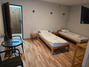 a room with two beds and a table and a television at Agroturystyka Chelosiowy Dworek in Piekoszów