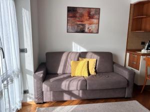a gray couch with two yellow pillows in a living room at Le Tre A - Sole in Folgaria