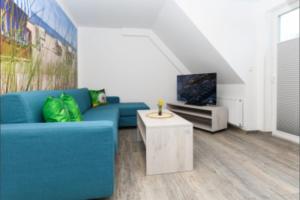 Una sala de estar con un sofá azul y un televisor en Haus Strandkorb FeWo Strandkob 7, en Bensersiel