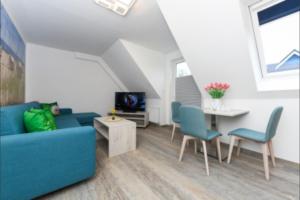 Una sala de estar con un sofá azul y una mesa. en Haus Strandkorb FeWo Strandkob 7, en Bensersiel