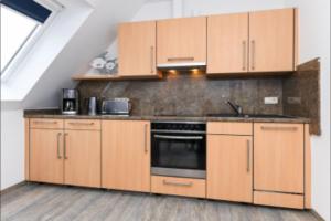 cocina con armarios de madera y fogones en Haus Strandkorb FeWo Strandkob 7, en Bensersiel