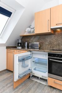 cocina con nevera abierta y fogones en Haus Strandkorb FeWo Strandkob 7, en Bensersiel 4 fotos más