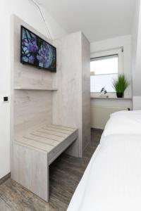 Un dormitorio con una cama y un televisor en una pared. en Haus Strandkorb FeWo Strandkob 7, en Bensersiel