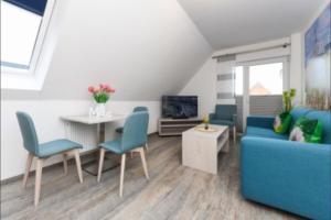 a living room with a blue couch and a table at Haus Strandkorb FeWo Strandkob 8 in Bensersiel