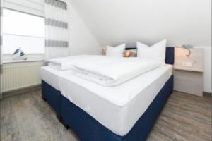 a bedroom with a large bed with white and blue at Haus Strandkorb FeWo Strandkob 8 in Bensersiel +7 photos