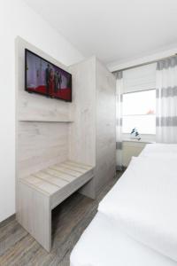 a white room with a television on a wall at Haus Strandkorb FeWo Strandkob 8 in Bensersiel