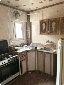 een kleine keuken met een fornuis en een spoelbak bij Roma apartment in Dumyat al Jadidah