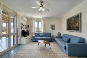 ファヴィニャーナにあるVilla Ficuriniaの青いソファ2脚とテレビのあるリビングルーム