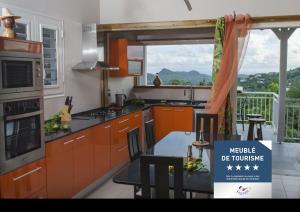 uma cozinha com armários laranja, uma mesa e uma janela em Residence Can' Hibiscus em Le Marin