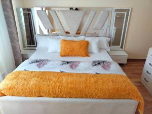 内罗毕Warm and Cosy 2 bedroom的一间卧室配有一张大白色床和橙色毯子 更多21张照片