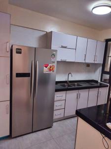 内罗毕Warm and Cosy 2 bedroom的配有不锈钢冰箱和白色橱柜的厨房