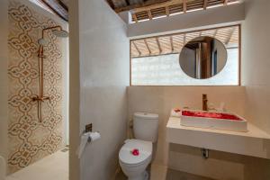 a bathroom with a toilet and a sink and a mirror at Sunset Joglo Pool Villa in Kerobokan +7 photos