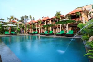 een zwembad in een resort met groene stoelen en parasols bij Ubud Tropical Garden in Ubud