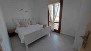 a white bedroom with a white bed and a window at Beach front Villa Pasithea in Monolithos