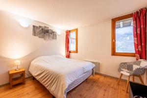 una camera da letto con un letto, una finestra e una sedia di Valloire - Appartement avec piscine a Valloire