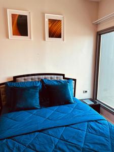 a bedroom with a blue bed with two pictures on the wall at 1BR at Thonglor BTS InfinityPool overlooking city in Bangkok +26 photos