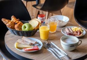 - une table avec une assiette de produits pour le petit-déjeuner et du jus d'orange dans l'établissement B&B HOTEL La Rochelle Centre Les Minimes, à La Rochelle