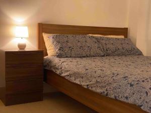 罗金汉姆Cosy, private guest house with pool and private parking的一间卧室配有一张床和一个带灯的床头柜