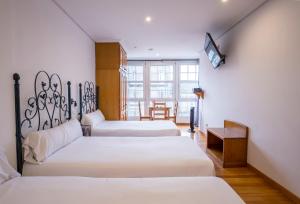 a room with three beds and a tv on a wall at InsideHome Porta do Sol in Vigo